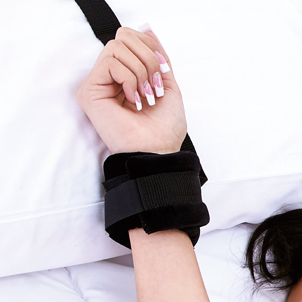 Hand with black wrist bondage on a white background