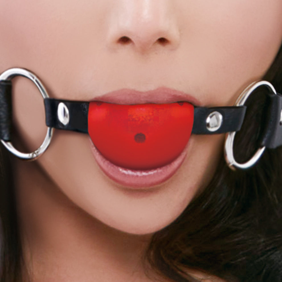 Close-up of a person wearing a red ball gag with black leather straps.
