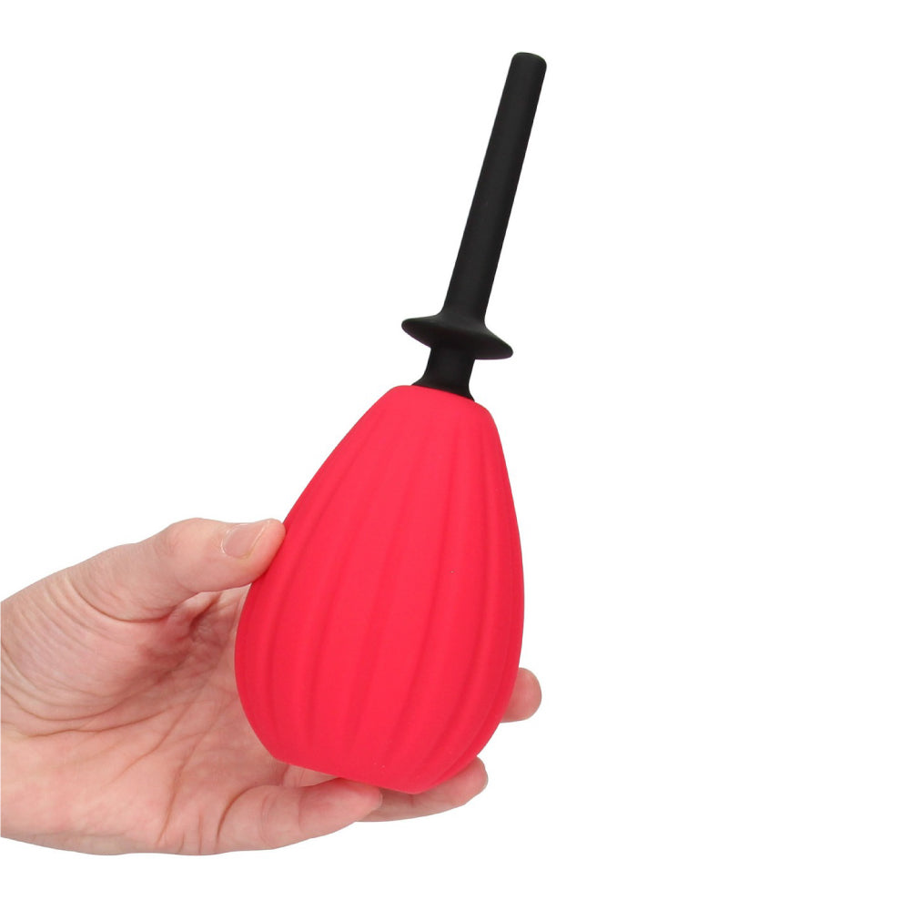 Aneros Prelude Enema Bulb with black nozzle and red pump being held on a white background