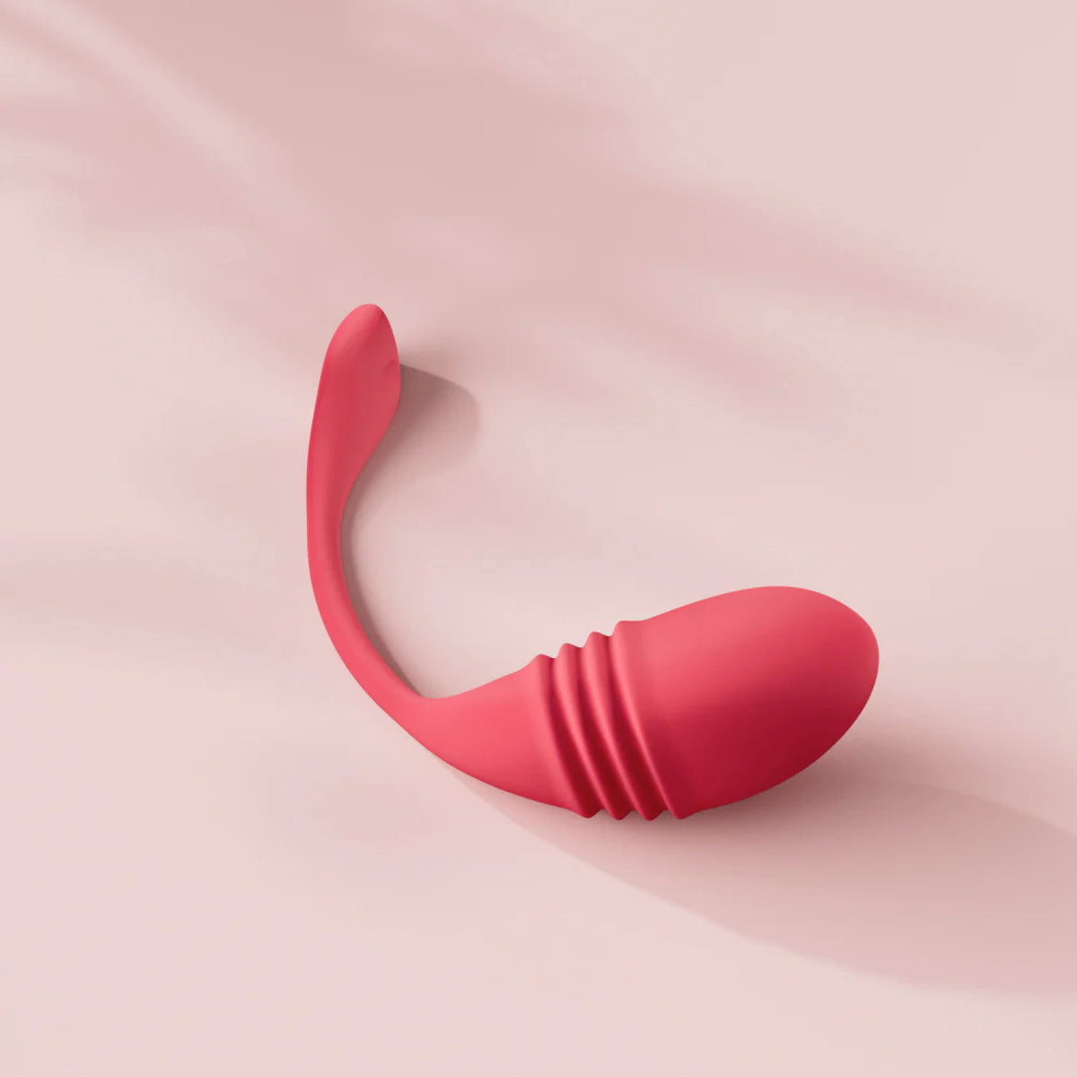 Lovense Vulse Rechargeable Silicone Thrusting Egg Vibrator on a pink background
